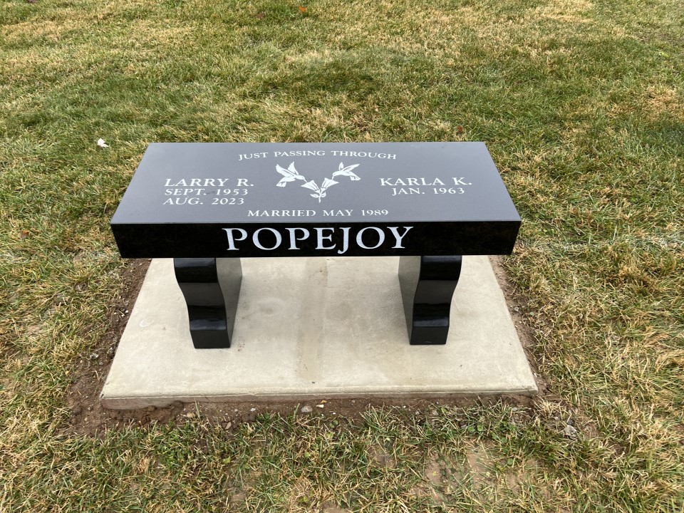 Black granite memorial bench with harp shaped curved legs and two doves etched on the seat