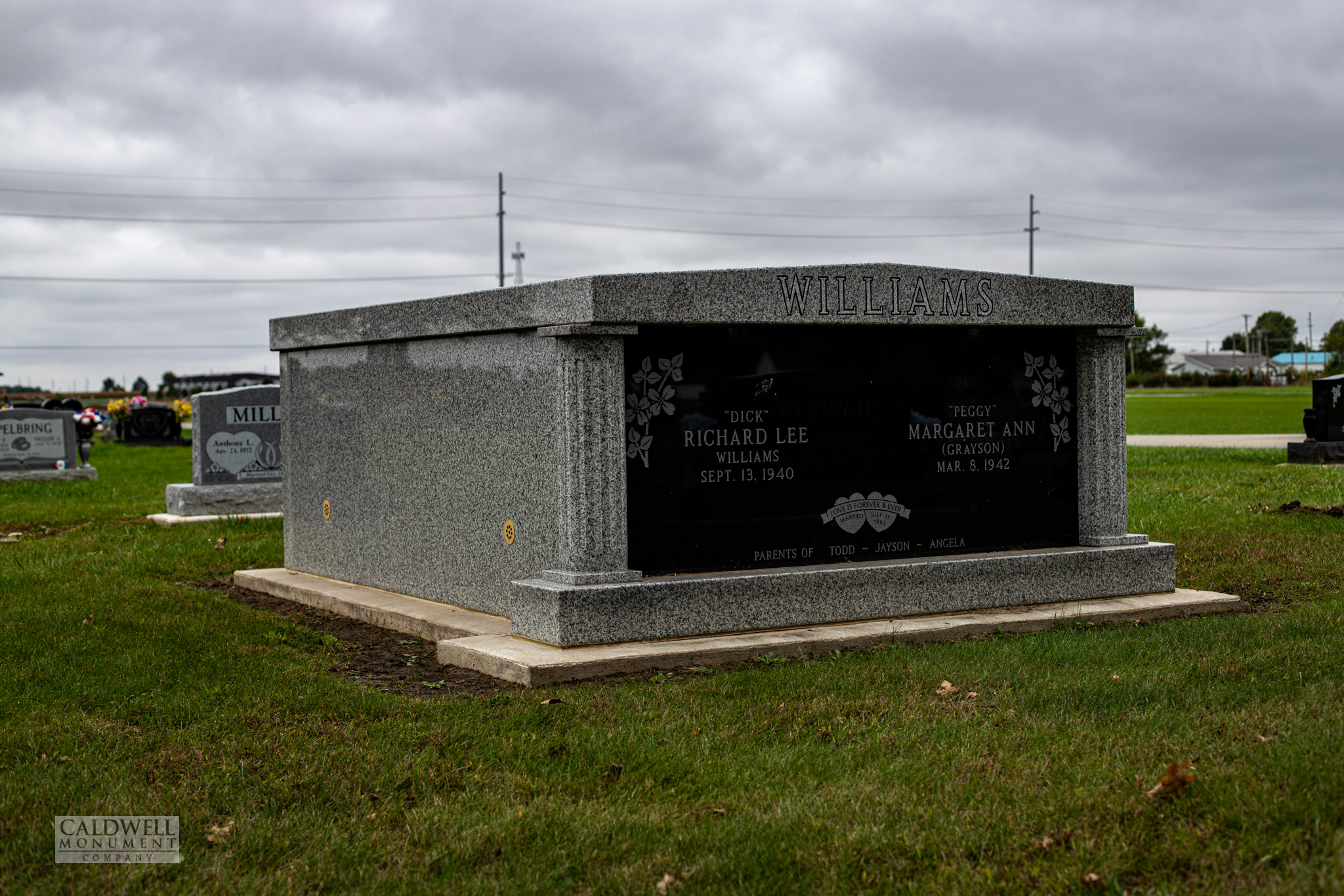 Two person granite mausoleum with a grey granite shell, fluted corner columns and a polished black front panel