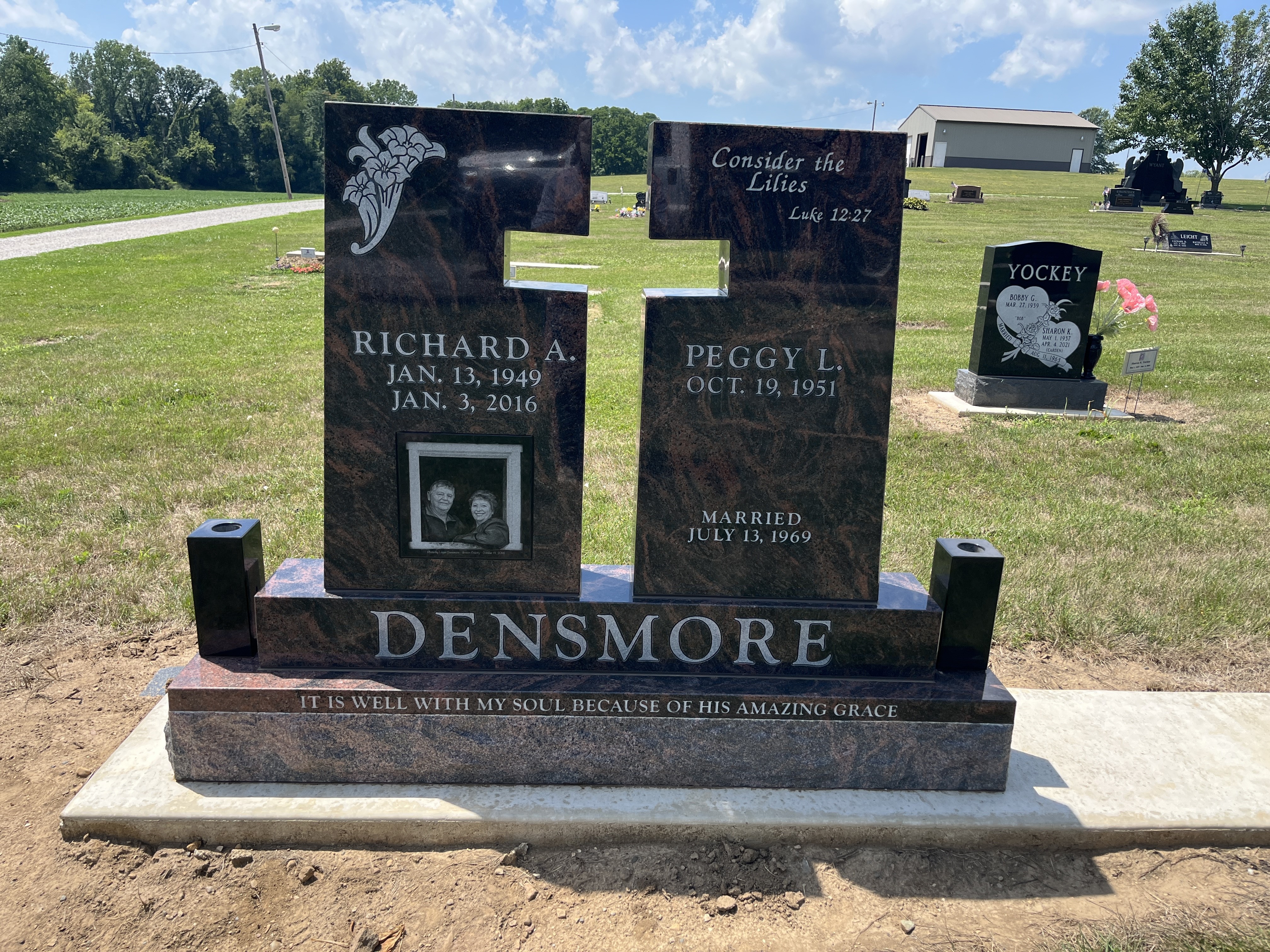 Two red granite tablets set apart so the gap between them forms a cross, with a laser etched portrait and carved lilies